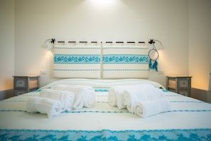 A neatly made bed with two pillows, a headboard with decorative patterns, and two bedside tables with lamps.