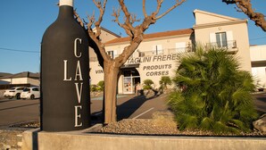 A building with a sign that reads 'CAVE' and another sign for 'TAGLINI FRERE PRODUCTS CORSES.' - Holiday Apartment "Poggio Mezzana" with Sea View, Shared Pool & A/C (Santa-Lucia-di-Moriani)