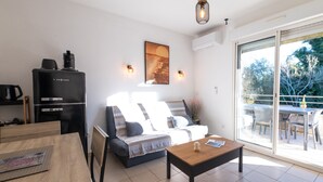 A living room with a sofa, coffee table, and a dining area with a table and chairs. - Holiday Apartment "Poggio Mezzana" with Sea View, Shared Pool & A/C (Santa-Lucia-di-Moriani)