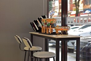 A table with a bowl, chopsticks, and a small figurine. There are two chairs and a window with a view of parked cars. - Xincai Hotel (Nanning Chaoyang Square Railway Station Subway Station Store) (Nanning)