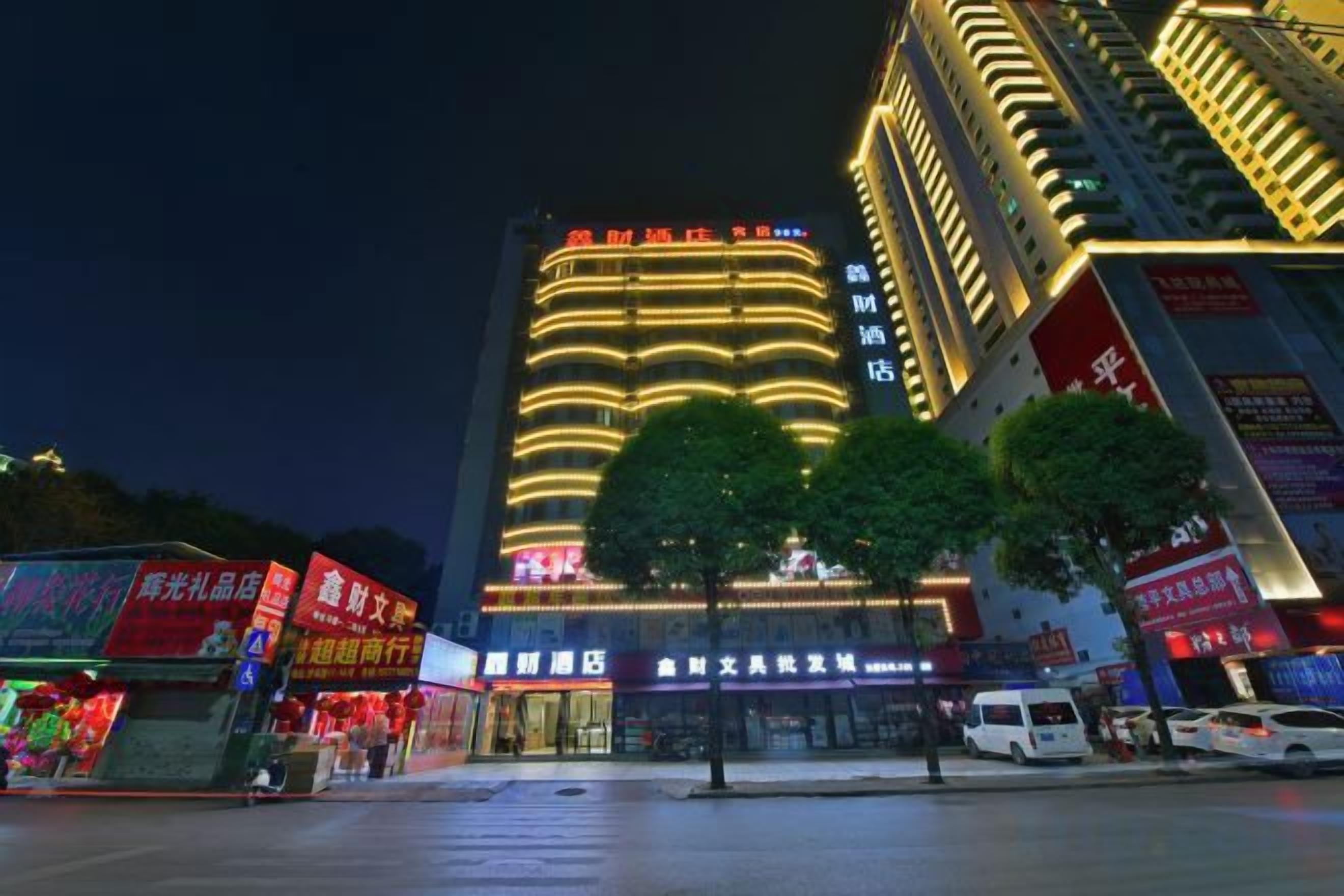 A multi-story hotel with illuminated signage, a central atrium, and a parking area.