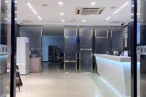 A reception area with a counter, glass partitions, and a refrigerator. - Xincai Hotel (Nanning Chaoyang Square Railway Station Subway Station Store) (Nanning)