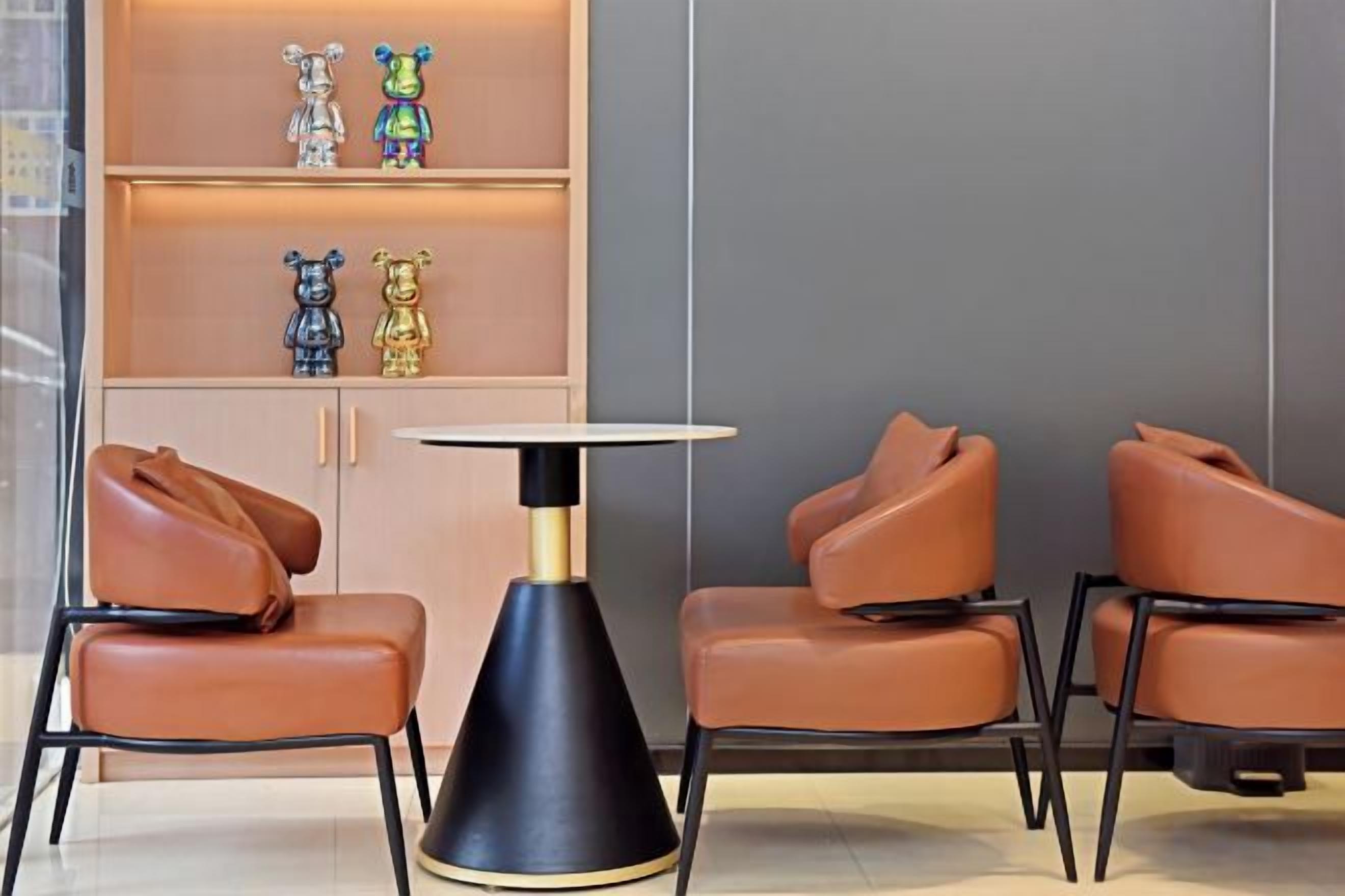 A seating area with leather chairs, a round table, and a shelf with decorative items.
