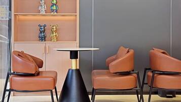 A seating area with leather chairs, a round table, and a shelf with decorative items.