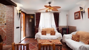 Een gezellige kamer met een bed, twee slaapbanken, een eettafel, een open haard en een plafondventilator.