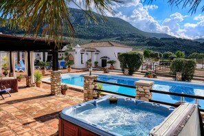 A pool area with a hot tub, lounge chairs, and a mountain backdrop. - Luxury holiday retreat, 2 pools, heated jacuzzi and free fibre optic WiFi and equestrian facilities (Málaga)