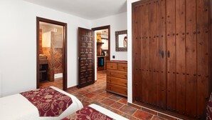 Een slaapkamer met twee bedden, een houten garderobe en een badkamer door een open deur zichtbaar.