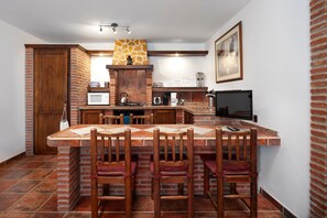 A kitchen with a stone fireplace, wooden cabinets, and a tiled floor. - Luxury holiday retreat, 2 pools, heated jacuzzi and free fibre optic WiFi and equestrian facilities (Málaga)