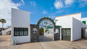 Edifici modern amb façana blanca, un arc central amb un logotip i un cel clar.
