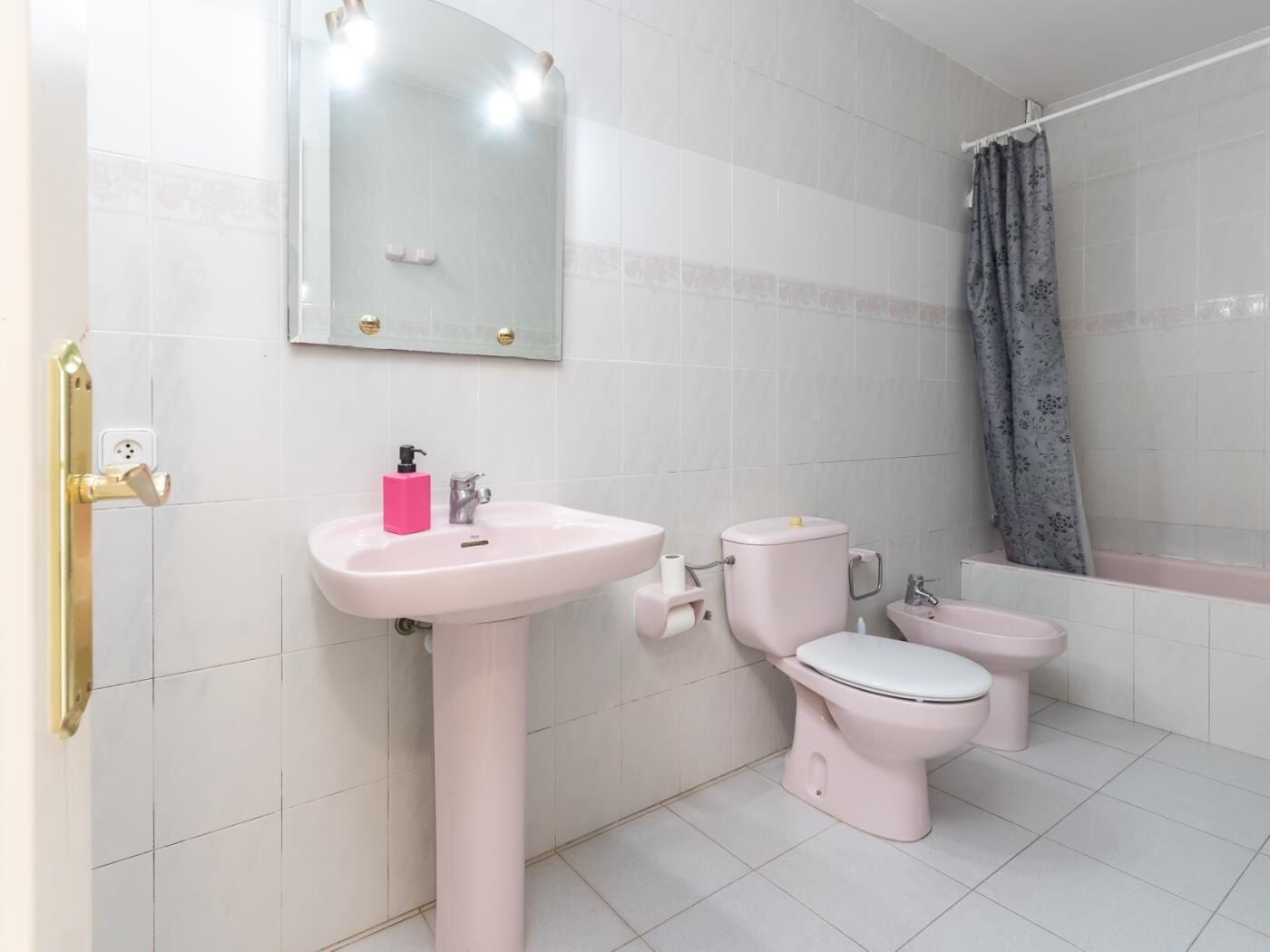 A bathroom with a sink, two toilets, a shower, and a mirror.