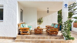 A covered outdoor seating area with wooden furniture and a potted plant.