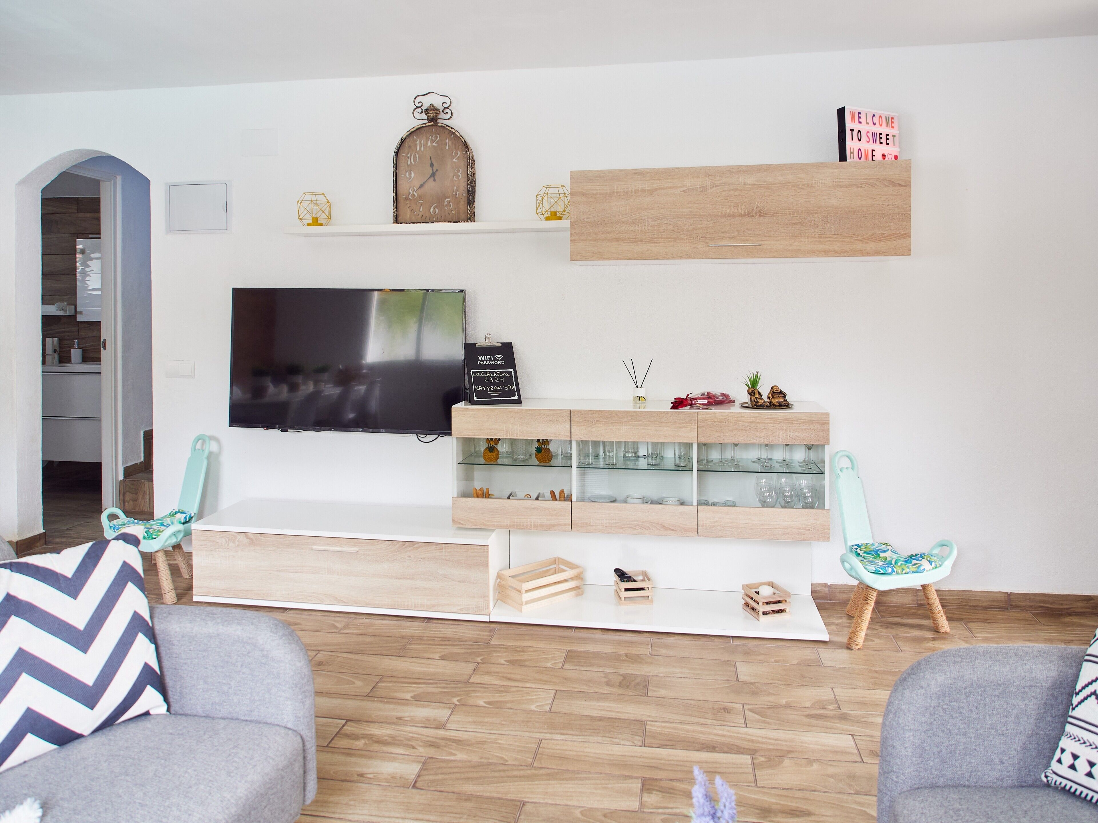 Una sala de estar moderna con un televisor, estanterías de madera y dos sillones.