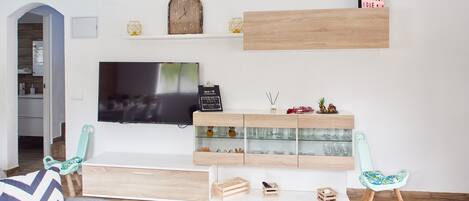 Una sala de estar moderna con un televisor, estanterías de madera y dos sillones.