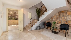 A modern interior with a staircase, a door leading outside, and two black chairs.