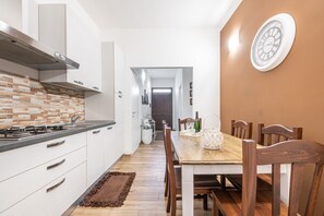 Une cuisine moderne avec des meubles blancs, une table à manger en bois et une horloge au mur.