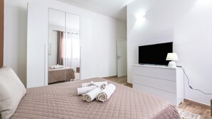 Une chambre à coucher avec un lit, une télévision, un miroir et une armoire.