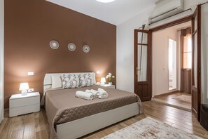 Une chambre à coucher comprenant un lit, des tables de chevet, une horloge murale et une porte donnant sur une autre pièce.