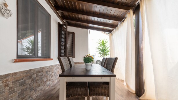 Un espace repas comprenant une table, des chaises, une plante en pot et une vue sur l’extérieur.