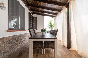 Un espace repas comprenant une table, des chaises, une plante en pot et une vue sur l’extérieur.