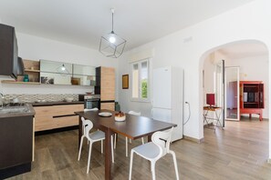 A modern kitchen with a dining area, wooden flooring, and a large window.