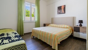 Un dormitorio con cama, mesita de noche, lámpara, ventana con cortinas y un cuadro en la pared.