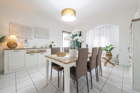 A modern dining area with a white table, brown chairs, a lamp, and decorative items.