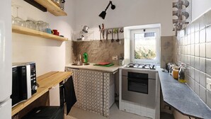 Een kleine keuken met een magnetron, fornuis en diverse keukengerei.