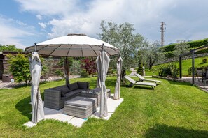 Un espace patio doté d’un coin salon abrité, d’une pelouse et d’un mur en pierre.
