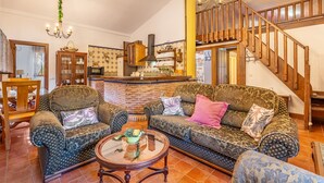Ein Wohnzimmer mit gemusterten Sofas, einem Holztisch und einer Treppe.