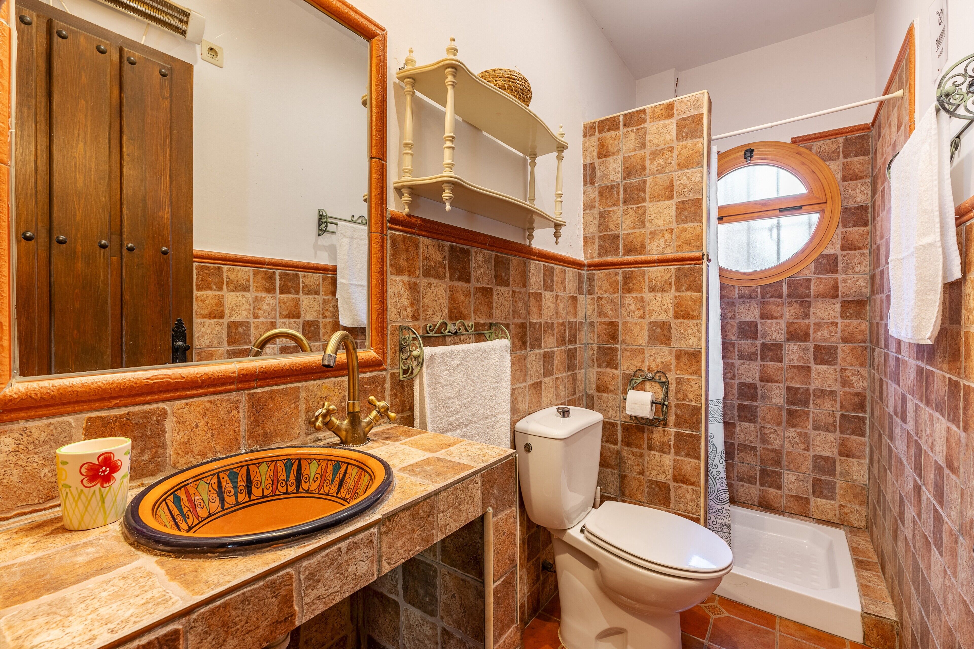 A bathroom with a sink, toilet, shower, and a mirror.