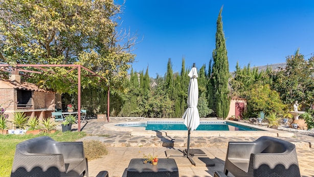 Eine Terrasse mit Gartenmöbeln, einem Pool und einer Pergola.