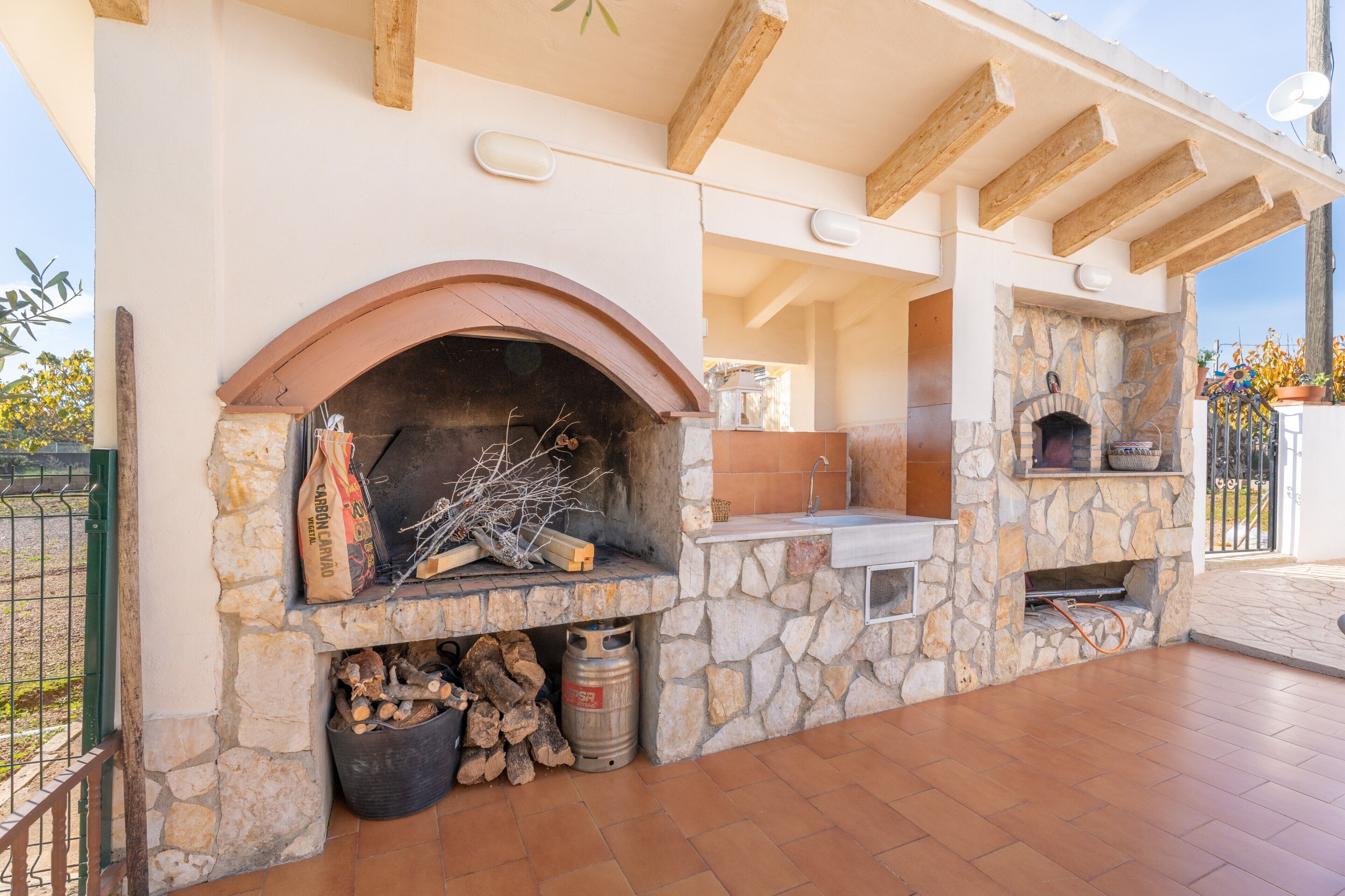 An outdoor kitchen area with stone walls, a stone oven, and a built-in sink.