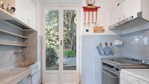 A kitchen with white cabinets, a marble countertop, a double door leading outside, a stove, and a clock on the wall. - Villa 'Uliveto' with Sea View, Wi-Fi and Air Conditioning (Camogli)