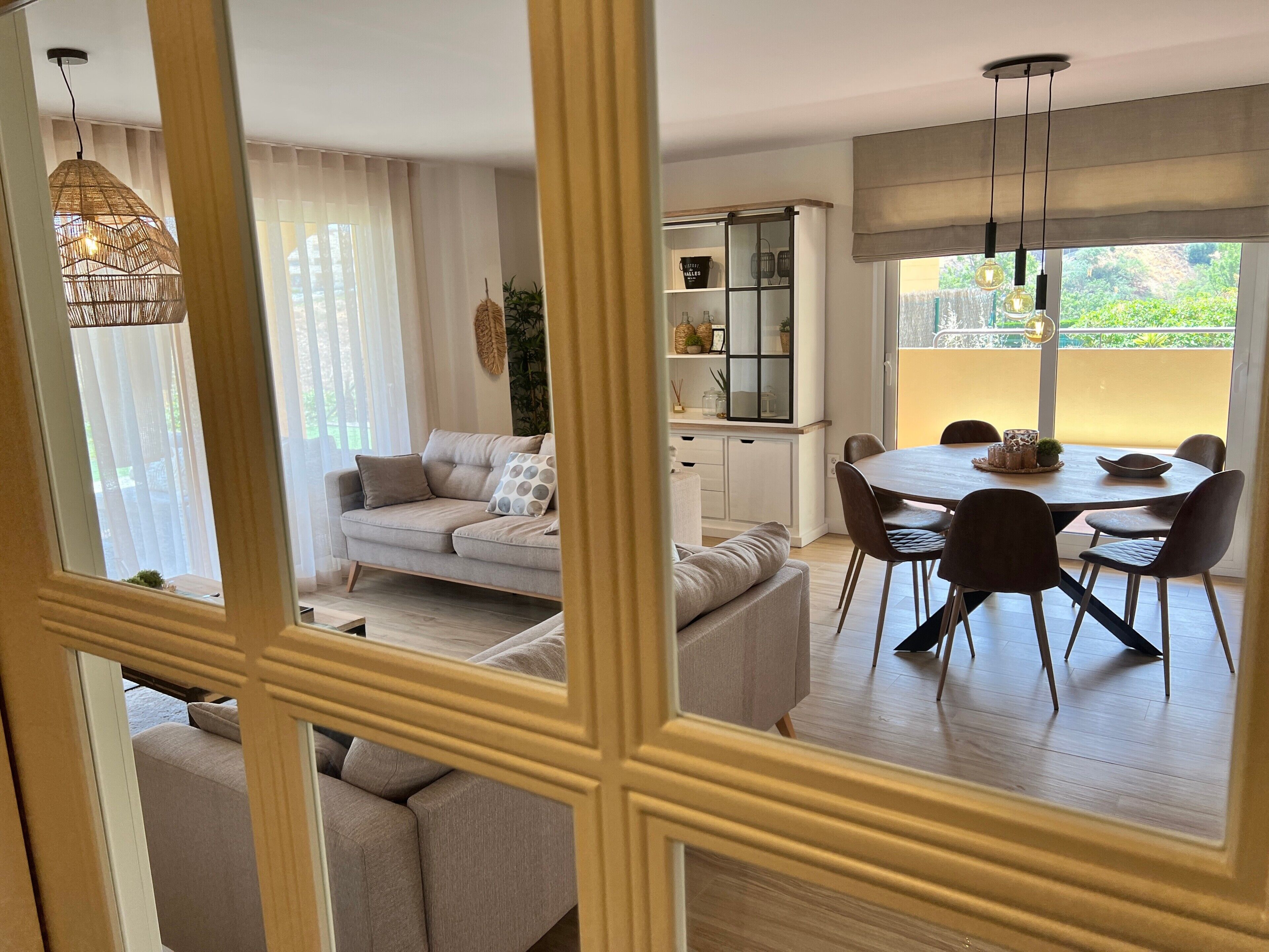 Un salon moderne avec un canapé, une table à manger, des chaises et une vue sur la verdure à l’extérieur.
