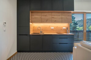 A modern kitchen with dark cabinetry, a wooden countertop, and a built-in sink.