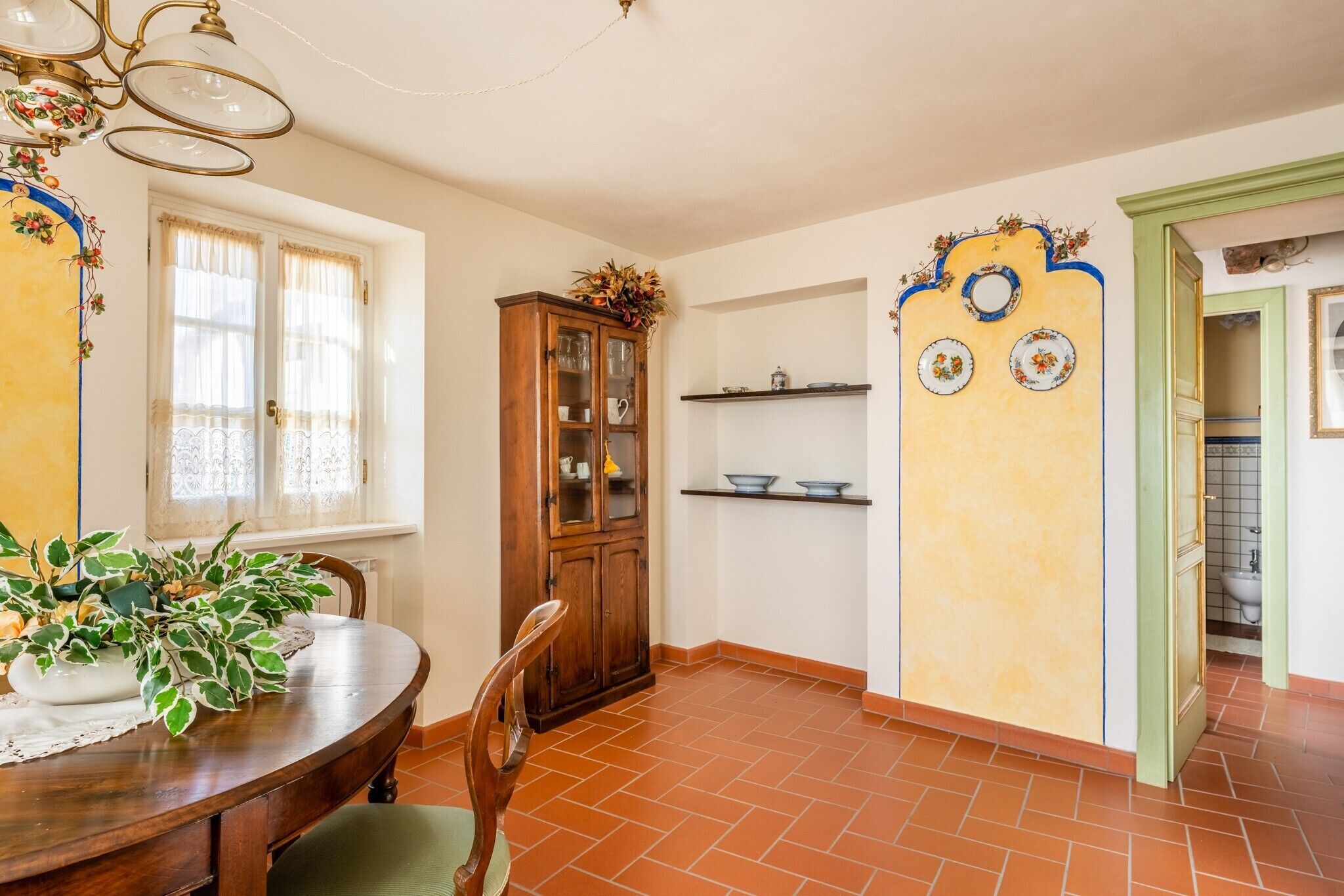 A dining area with a wooden table, chairs, a cabinet, and a window with curtains.