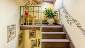 Una escalera con barandilla de madera, baranda de metal verde y una planta en maceta.