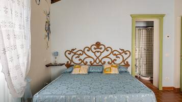 Un dormitorio con cama, mesita de noche, pared decorativa y puerta al baño.