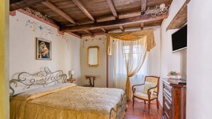 A bedroom with a bed, a chair, a dresser, a TV, and a decorative mirror.