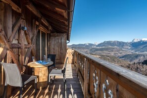 Une terrasse en bois avec une table et des chaises, offrant une vue sur un paysage montagneux.