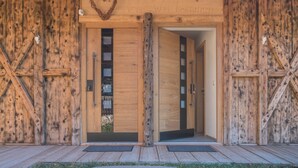 A wooden building with a heart-shaped wreath, double doors, and a wooden staircase leading inside. - Apartment "Aschnerhof Holzhitt" with Mountain View, Private Balcony & Wi-Fi (Renon)