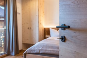 Une chambre à coucher avec un lit en bois, une table de chevet et une fenêtre avec des rideaux.