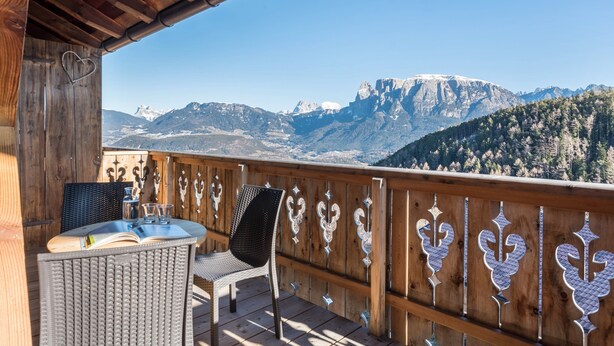 A wooden deck with a table and chairs, overlooking a mountainous landscape. - Apartment "Aschnerhof Holzhitt" with Mountain View, Private Balcony & Wi-Fi (Renon)