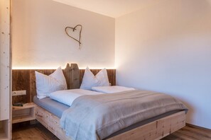 A wooden bed with a headboard, a bedside table, and a wall-mounted heart decoration.
