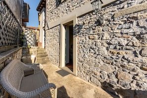 A stone building with a doorway, a wicker chair, and a small table. - Apartment 'Limoni' with Private Terrace (Molazzana)