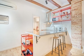 Une cuisine avec un îlot central, des tabourets, un four à micro-ondes et un mur en briques.