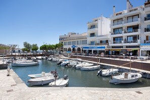 Un puerto deportivo con barcos amarrados, un restaurante frente al agua y un edificio de varios pisos con balcones.