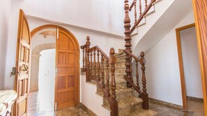 A wooden staircase with a marble floor, a wooden door, and a white wall.