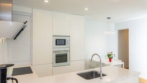 Una cocina moderna con electrodomésticos integrados, un lavaplatos y una zona de comedor con una mesa y sillas.