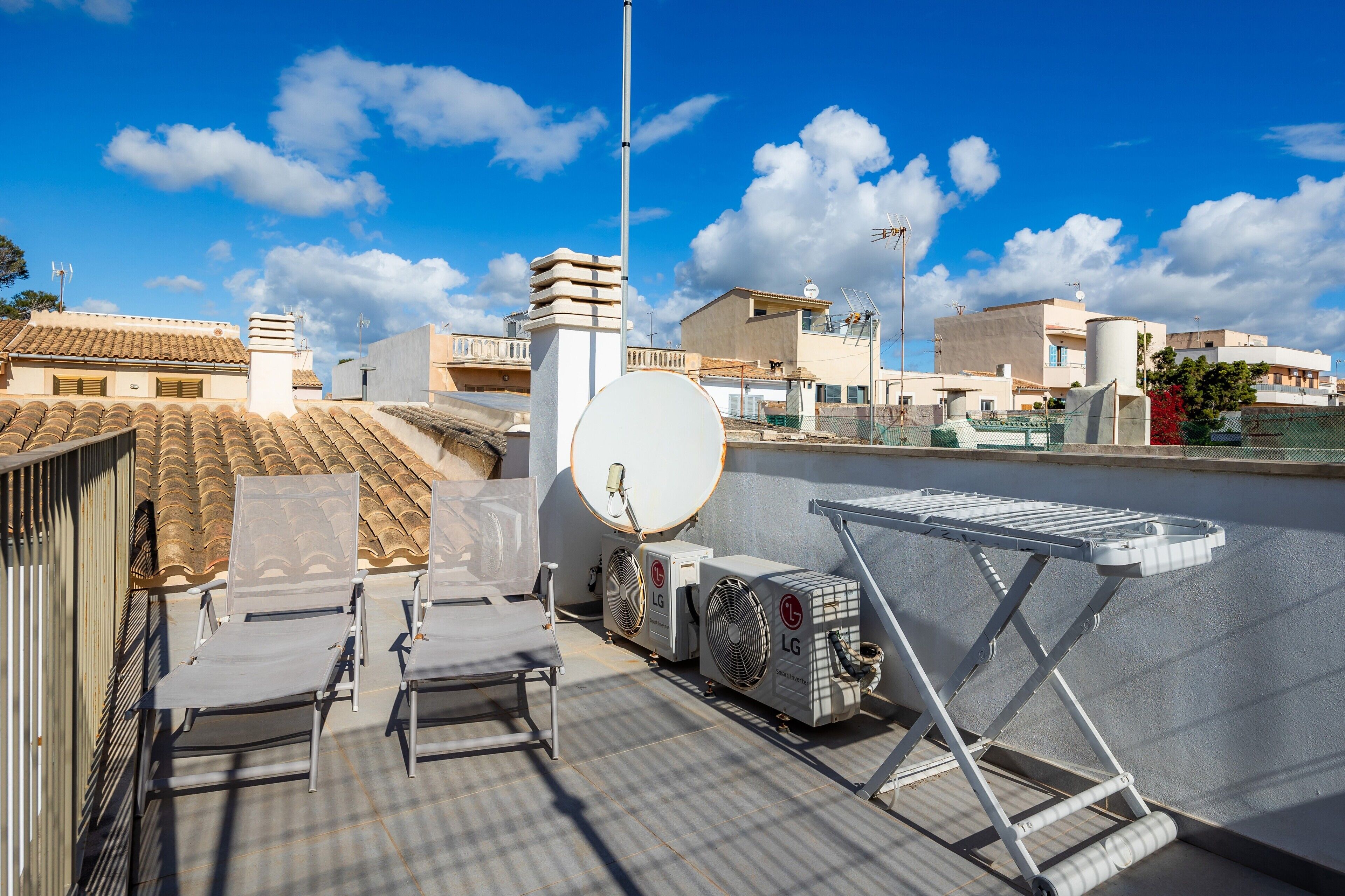 A rooftop terrace with air conditioning units, a satellite dish, and a drying rack.